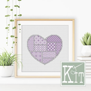 May include: Framed cross-stitch heart with a patchwork design in shades of purple and black. The heart is composed of various geometric patterns. The framed artwork is displayed on a white shelf with a small potted plant and a "Kit" logo.