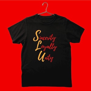 May include: Black t-shirt featuring the words "Sincerity, Loyalty, Unity" in a cursive font. The text is in yellow and red. The shirt is displayed on a silver hanger against a red backdrop. The t-shirt is a standard fit.