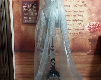 May include: A light blue tulle cape with silver glitter snowflakes. The cape is on a dress form.