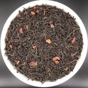 May include: A white bowl filled with loose leaf black tea with small pieces of dark chocolate.