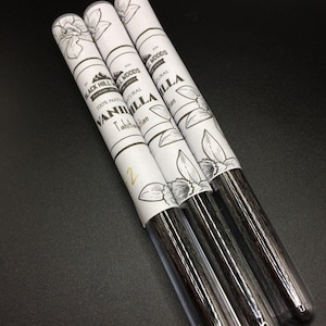 Puede incluir: Tres tubos de vidrio que contienen vainas de vainilla. Los tubos están etiquetados con "Black Hill Woods" y "100% Vainilla de Tahití Natural".