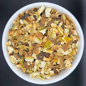 May include: A white bowl filled with dried orange peel pieces. The peel is a mix of light and dark brown colours.
