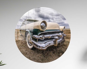 May include: A vintage, light green and cream colored car with chrome accents. The car is parked in a field with a cloudy sky in the background.