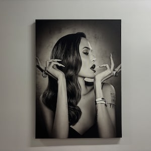 Può includere: Fotografia in bianco e nero di una persona con lunghi capelli scuri, che indossa una camicetta nera e gioielli. La persona sta guardando di lato e ha la bocca leggermente aperta.