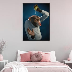 May include: A framed art print depicts a chimpanzee in a white shirt, with its head open and a lemon being squeezed into it. The background is a gradient of dark blue. The artwork is displayed above a bed with pink pillows and a white comforter.