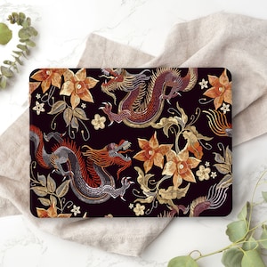 May include: A laptop skin with a black background and a repeating pattern of gold and orange dragons and flowers.