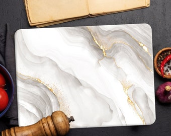 May include: White marble cutting board with gold veining. The board is on a black surface with a bowl of tomatoes, a pepper grinder, a bowl of spices, and a clove of garlic.