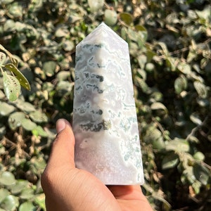 May include: A white and green agate crystal point with a pointed tip and a flat base. The crystal has a unique pattern of green and white swirls.