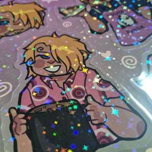 May include: A holographic sticker featuring a cartoon character with blonde hair holding a black mug. The character is wearing a pink and white shirt with a star pattern. The background is a purple and white holographic pattern with stars.