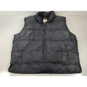 May include: A dark gray puffer vest with a full-length zipper closure. The vest has a high collar and two front pockets. The material appears to be a nylon or similar synthetic fabric. The vest is designed to provide warmth and insulation.