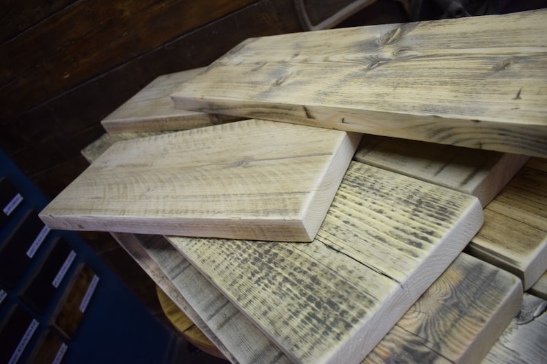 Op de afbeelding: Een stapel gerecyclede houten planken, die de natuurlijke nerf en knoesten van het hout laten zien. De planken zijn verweerd en hebben een rustieke uitstraling.