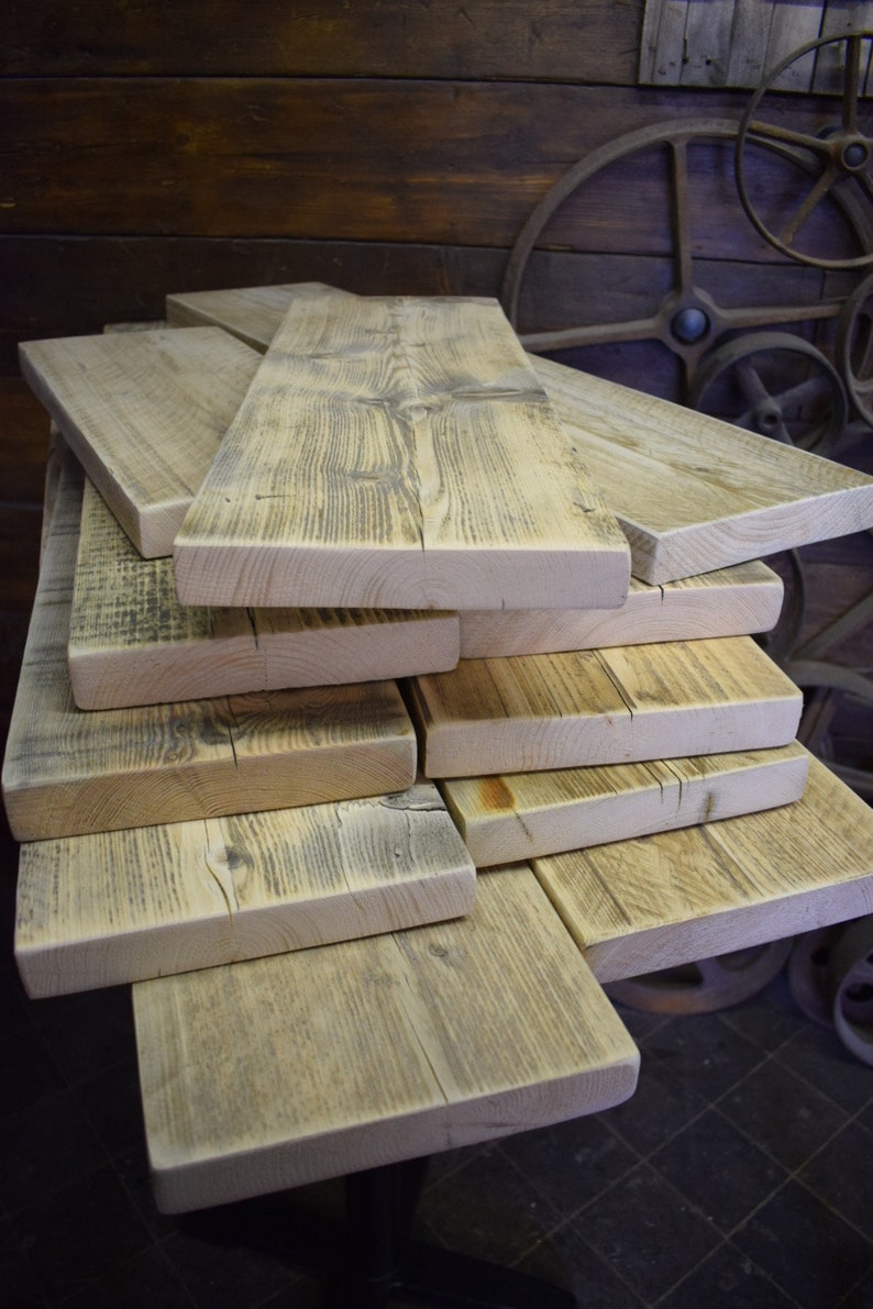 Op de afbeelding: Een stapel gerecyclede houten planken, elk met een uniek nerfpatroon en een verweerde, rustieke uitstraling. De planken zijn in een verspringende stapel gelegd, wat een visueel aantrekkelijk beeld cre&euml;ert.