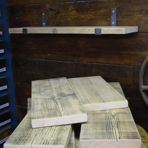 Op de afbeelding: Een stapel gerecyclede houten planken met een natuurlijke afwerking. De planken zijn gemaakt van ruw gezaagd hout met knoesten en nerven. De planken zijn op elkaar gestapeld, wat een rustieke en industri&euml;le uitstraling geeft.