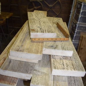May include: A stack of reclaimed wood planks, some with a weathered grey finish, others with a natural wood colour. A ruler is placed on top of the planks, measuring 20.3 cm.