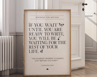 May include: A framed print with a light wood frame. The print has a cream background with black text that reads "REMINDER FOR WRITERS" and a quote by Stephen King. The quote is about writing and includes butterfly and pen graphics.