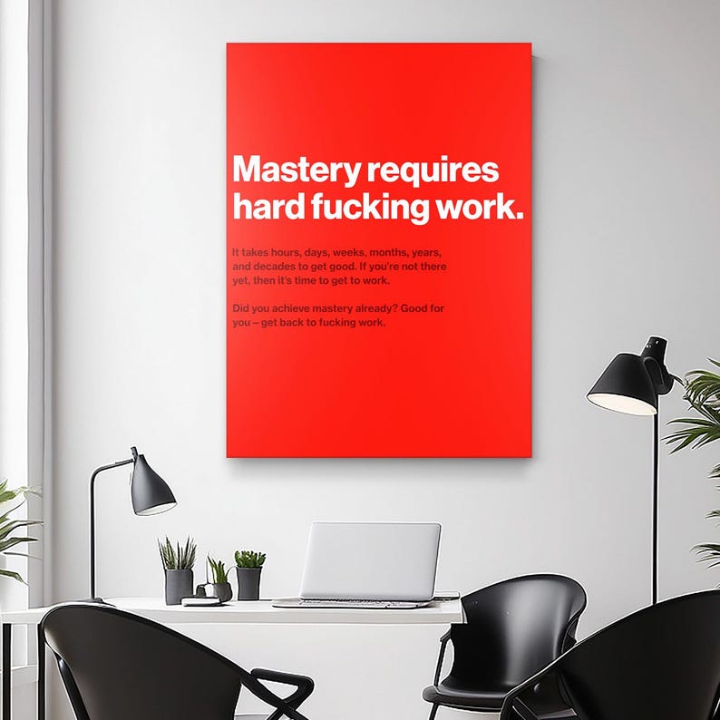 Puede incluir: Un lienzo rojo con texto blanco que dice "Mastery requires hard fucking work." Texto adicional debajo indica el tiempo que se tarda en lograr el dominio. La impresi&oacute;n se muestra en un entorno de oficina moderno.