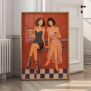 May include: A framed art print depicts two figures seated at a table, each holding a cocktail. One figure wears a black dress and blue heels, the other a pink dress and red heels. The background is red, with a checkered floor.