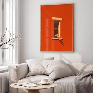 May include: A framed art print featuring a vibrant orange wall with a window. The window frame is light brown, and the artwork depicts legs in blue shorts resting on the window sill. The artwork is displayed in a living room setting.