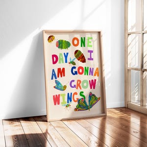 Pu&ograve; includere: Una stampa artistica incorniciata con le parole "ONE DAY I AM GONNA GROW WINGS" in lettere colorate. La stampa presenta illustrazioni di un bruco, farfalle e insetti. La cornice &egrave; di colore legno chiaro.