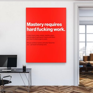 Puede incluir: Una impresi&oacute;n de arte mural rectangular roja con texto blanco que dice "Mastery requires hard fucking work". Texto adicional debajo indica el tiempo que se tarda en lograr el dominio. La impresi&oacute;n se muestra en un entorno de oficina moderno.