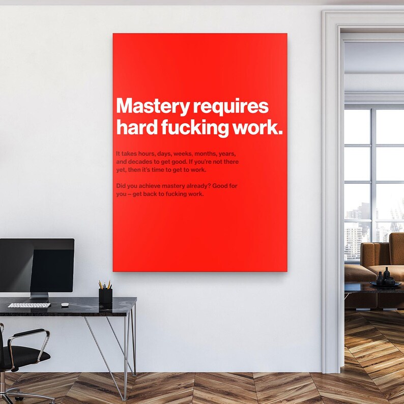 Puede incluir: Una impresi&oacute;n de arte mural rectangular roja con texto blanco que dice "Mastery requires hard fucking work". Texto adicional debajo indica el tiempo que se tarda en lograr el dominio. La impresi&oacute;n se muestra en un entorno de oficina moderno.