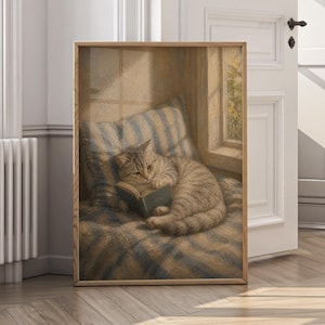 May include: A framed print depicts a tabby cat engrossed in reading a small book. The cat rests on a striped pillow and blanket, bathed in soft light from a nearby window. The artwork is set in a wooden frame.