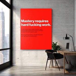 Puede incluir: Un cuadro rectangular rojo con texto blanco que dice "Mastery requires hard fucking work." Texto adicional debajo indica el tiempo necesario para lograr el dominio. El arte se exhibe en un entorno de oficina moderno.