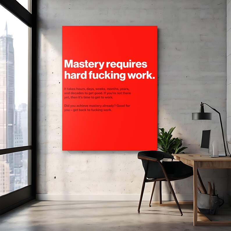 Puede incluir: Un cuadro rectangular rojo con texto blanco que dice "Mastery requires hard fucking work." Texto adicional debajo indica el tiempo necesario para lograr el dominio. El arte se exhibe en un entorno de oficina moderno.