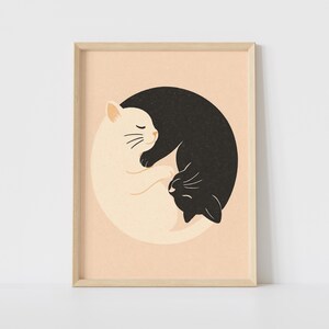 Könnte beinhalten: Gerahmter Kunstdruck mit einem Yin-Yang-Motiv aus einer schwarzen und einer weißen Katze. Die Katzen sind vor einem sanften Pfirsichhintergrund verschlungen. Das Kunstwerk ist in einem hellen Holzrahmen gefasst, ideal für die Inneneinrichtung.
