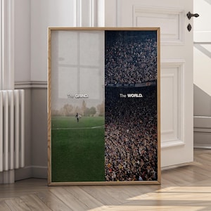 May include: Framed art print with a split design. One side shows a person on a green field, the other a stadium crowd. Text reads "The Grind" and "The World.". The frame is a light brown color.
