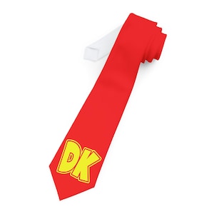 Peut inclure: Une cravate rouge avec un logo "DK" jaune. La cravate est en tissu lisse et a une doublure blanche.