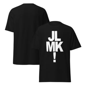 May include: A black short-sleeved t-shirt featuring the white text JL MK! printed in a bold, stacked sans-serif font on the front. The garment is shown from both the front and back angles, displaying a solid black fabric construction throughout.