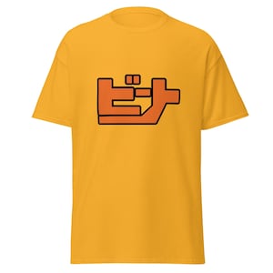 Peut inclure: Un t-shirt jaune avec un contour noir d'un caractère japonais en orange. Le caractère est "ビ", qui est le mot japonais pour "Beat".