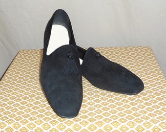 May include: A pair of black suede loafers with tassels. The loafers have a pointed toe and a slip-on design.