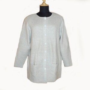 May include: A light gray cardigan with a button-up front and two pockets. The cardigan is made of a soft, knitted fabric.