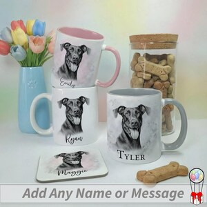 May include: White ceramic mugs with dog portraits and names, including "Emily", "Ryan", and "Tyler". A matching coaster with "Maggie" and a jar of dog biscuits are also present. A vase of tulips and a dog treat complete the scene.