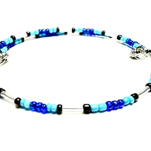 Op de afbeelding: Een zilveren armband met blauwe en lichtblauwe glazen kralen en zwarte kralen.