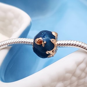 Peut inclure: Un charme bleu et or avec un motif de poisson. Le charme est en métal et a une finition brillante. C'est un style de charme populaire pour les bracelets.