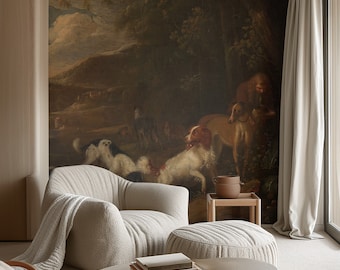 Op de afbeelding: Een woonkamer met een groot schilderij van een boslandschap met honden en een persoon. Het schilderij hangt aan de muur achter een witte fauteuil en een witte poef. Er liggen boeken op een salontafel voor de poef.