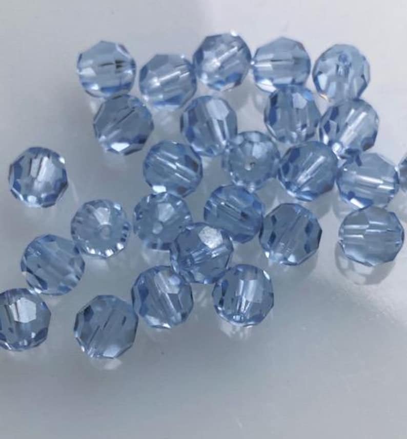 Puede incluir: Una colecci&oacute;n de cuentas de vidrio facetadas de color azul claro. Las cuentas son redondas y tienen un acabado brillante.