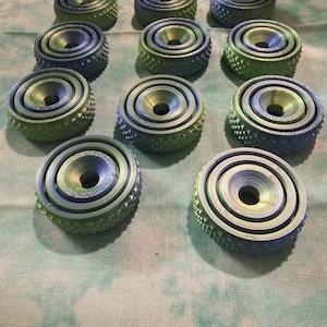 May include: Twelve green and blue concentric circle rings with a raised center, each ring has a textured surface.