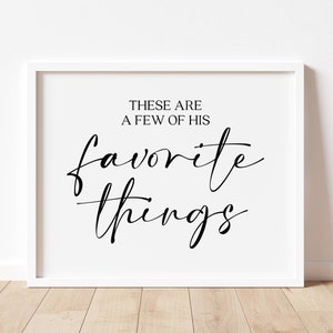 May include: A white framed print with black calligraphy that reads "These are a few of his favorite things."