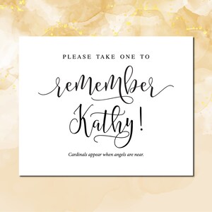 May include: White card with black text that reads "Please take one to remember Kathy!" and "Cardinals appear when angels are near."