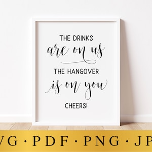 Op de afbeelding: Witte ingelijste poster met zwarte kalligrafietekst die luidt: "De drankjes zijn voor ons, de kater is voor jullie. Proost!"