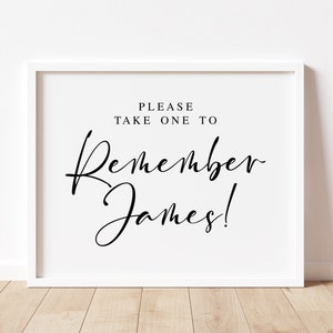 May include: White framed sign with black text that reads "Please take one to Remember James!"