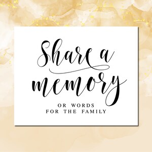 以下が含まれることがあります： 「Share a memory or words for the family」と黒の書道で書かれた白いカード。カードは、薄い茶色と金色のキラキラした背景の上に置かれています。
