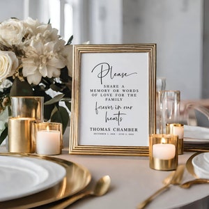 May include: A gold-framed sign with a white background and black text that reads "Please share a memory or words of love for the family forever in our hearts Thomas Chamber December 1, 1956 - June 2, 2025".