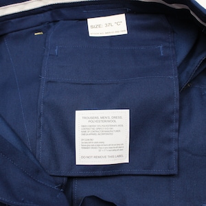 Puede incluir: Un pantal&oacute;n de vestir azul marino con una etiqueta blanca que dice "Trousers, Men's, Dress, Polyesterwool" y una etiqueta blanca con el texto "Defense Logistics Agency by GSA Apparel Incorporated".