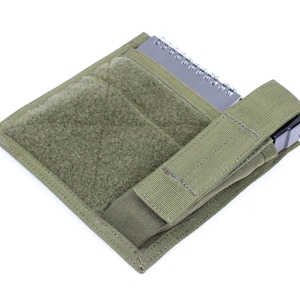 May include: A green tactical pouch with a velcro panel and a magazine holder. The pouch is designed to be attached to a belt or vest.