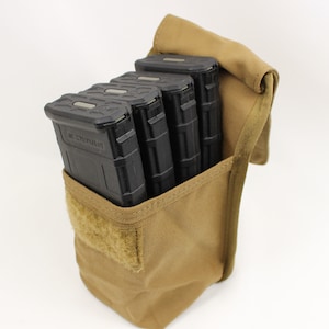 May include: A tan fabric pouch with a velcro closure, holding four black magazine pouches. The pouch is designed to carry multiple magazines for tactical use.